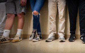 Students legs lined up against wall.